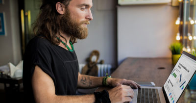 beard, punk, greasy, white guy, computer, poor, in debt, credit, bad credit, tattoos, laptop, table, desk, sad